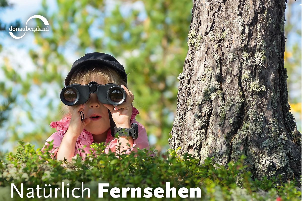 Text: Natürlich Fernsehen; Kind versteckt sich und schaut durch ein Fernglasd
