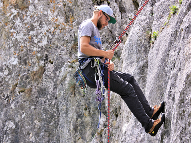 Man Klettert mit Sicherung an einer Felswand