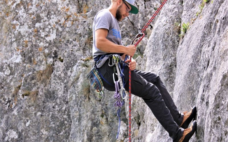 Man Klettert mit Sicherung an einer Felswand